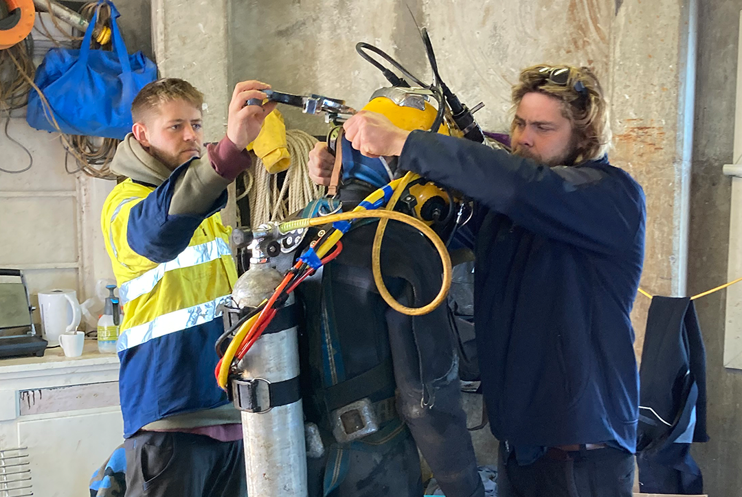 A diver is fitted with a drysuit.